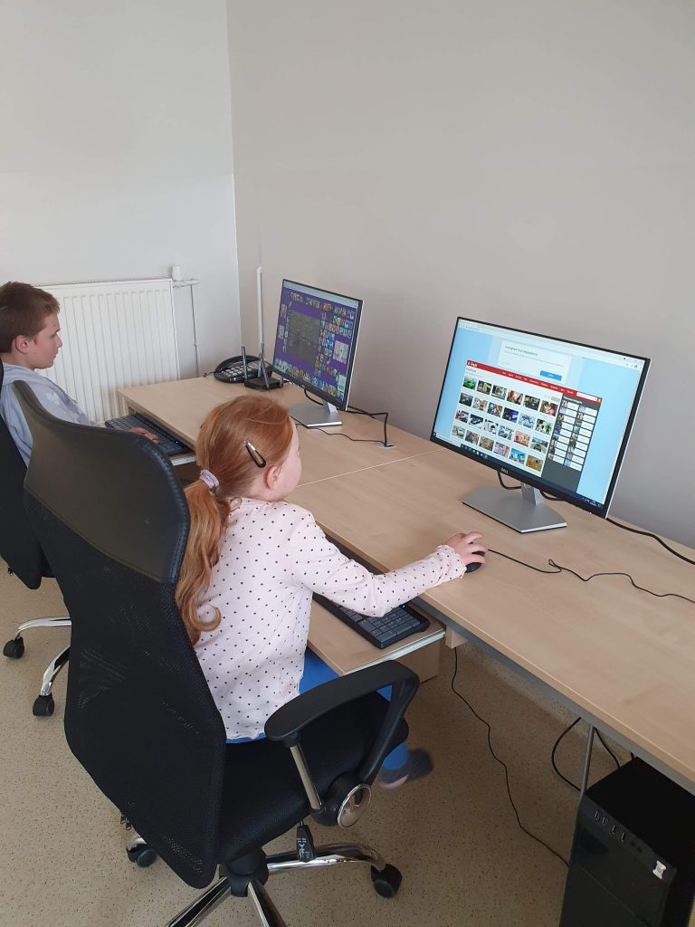 dwójka dzieci siedząca przy komputerach