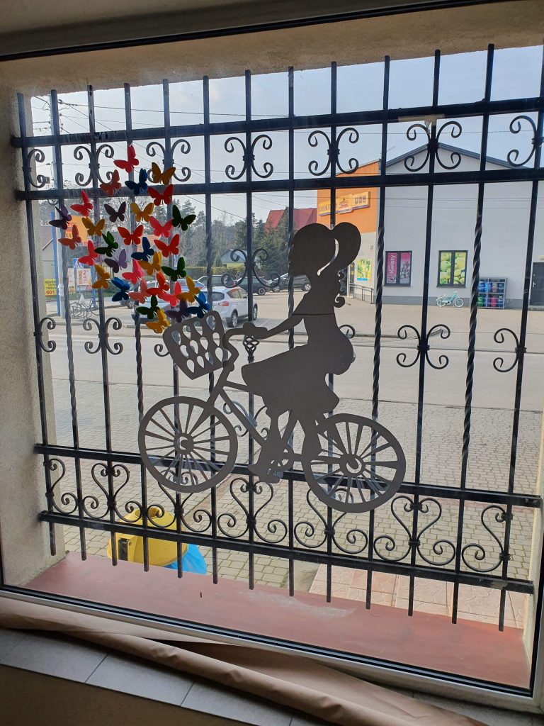 dziewczynka na rowerze jako krata okna